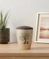 Preview: Decorative pet urn for cats in beige with a velvety surface and brown lid, adorned with a pad printed motif of an artistic tree of life and a sitting cat – A stylish and tranquil memorial for your loss.